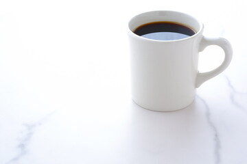 お気に入りのマグカップに淹れたてのコーヒーを入れ、一服を楽しむ朝の風景のイメージ
