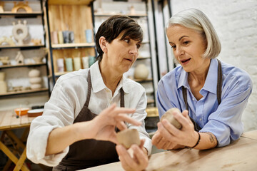 Obraz premium A lesbian couple works together on pottery projects in a cozy studio.
