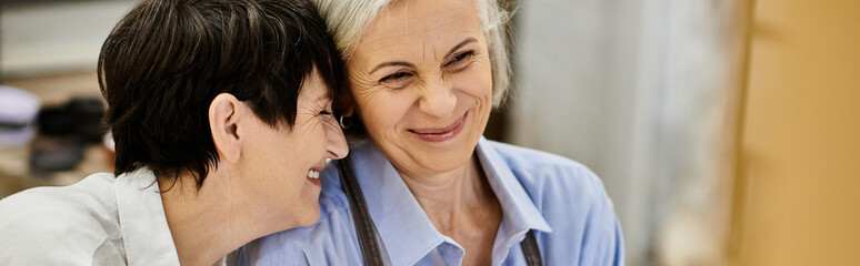 A mature lesbian couple shares a moment of laughter during a pottery session.