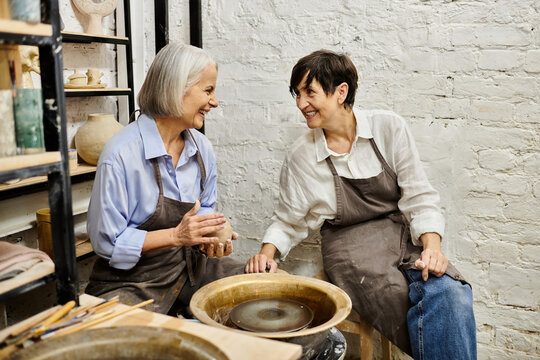 Two women in a pottery studio, one working on a clay piece.