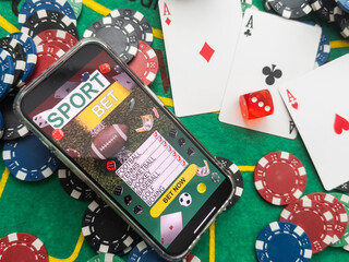 Smartphone with poker table on screen, playing cards and chip cards on poker table. Online casino.
