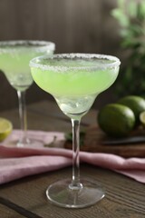 Delicious Margarita cocktail in glass on wooden table, closeup