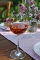 Glass of rose wine on table served for romantic date in garden