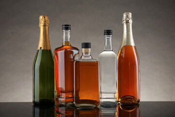 Bottles of different alcoholic drinks on table against gray background