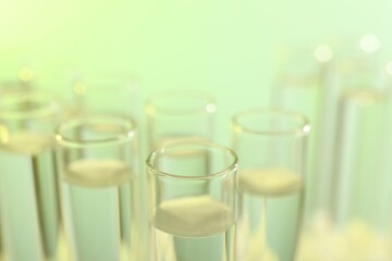 Many glass test tubes on yellow background, closeup