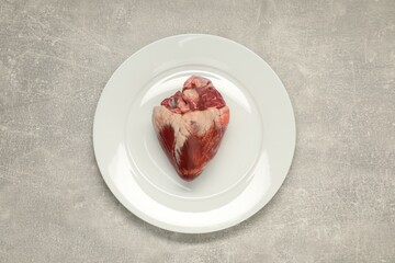 Raw heart on grey table, top view