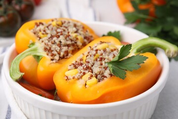 Quinoa stuffed bell pepper and parsley in bowl on light table, closeup
