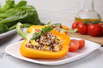 Quinoa stuffed bell pepper with basil on light table, closeup