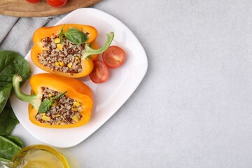 Quinoa stuffed bell pepper with basil and tomato on light table, top view. Space for text