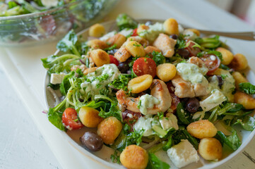 Delicious summer salad with chicken meat, vegetables, feta cheese, gnocchi and dressing