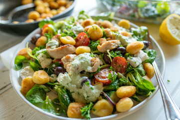 Delicious summer salad with chicken meat, vegetables, feta cheese, gnocchi and dressing