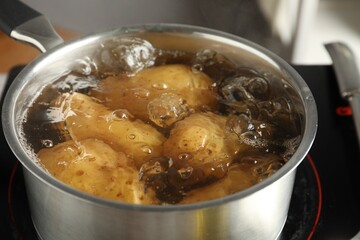 Boiling potatoes in saucepan on stove, closeup