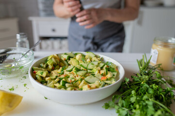 Homemade healthy food. Woman with apron with fresh prepared and healthy summer salad made with avocado, cucumber and apples