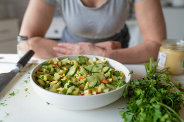 Homemade healthy food. Woman with apron with fresh prepared and healthy summer salad made with avocado, cucumber and apples