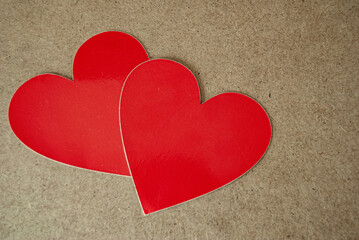 Two red hearts on a brown background, symbolizing love and warmth with a simple yet striking contrast.