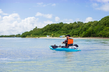 tourist with paddle in a sea blue kayak in a tropical bay 