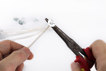 pliers is used to squeeze wick tab with cotton wick, during scented candle process with background...