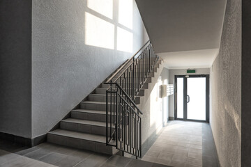 Staircase inside the entrance of a modern building. There is a bright light from outside, there is...