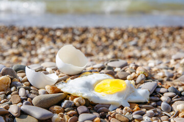 A chicken egg was fried in the sand. Hot weather on the beach.