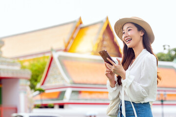 Asian female tourist using phone in front a famous landmark in Bangkok, Thailand