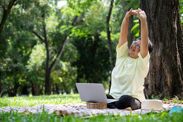 Happy Asian senior woman using laptop for working online outside office. Elderly retirement using...