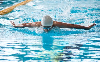 Swimmer boy swims butterfly swimming style in the pool