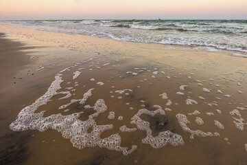 Patterns in foam left by retreating waves on the beach of Inhassoro, Mozambique, at dusk.