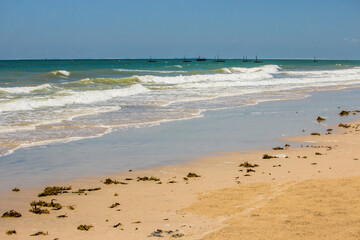 Waves breaking on the sandy beach of Inhassoro in Mozambique, with distant trsditional dhows on the horizon.