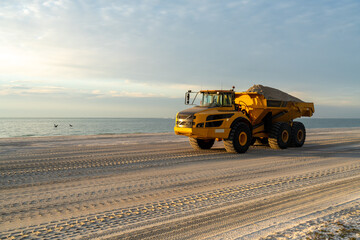 A loaded articulated hauler mining type dump truck carrying sand for a restoration project on a...