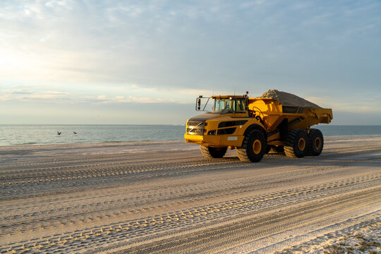 A loaded articulated hauler mining type dump truck carrying sand for a restoration project on a beach, Sanibel Island, Florida