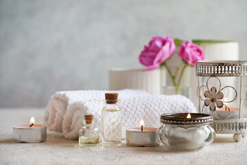 Bottles of aromatherapy essential oil with candles, rose de Mai flowers and spa treatment accessories on white background