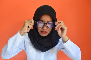 Beautiful young Asian business woman wearing white shirt and black hijab smiling, showing, with raised hand gesture and wearing glasses isolated on orange background