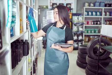 latin american saleswoman entrepreneur holding a digital tablet and oil container in an auto parts supply store	