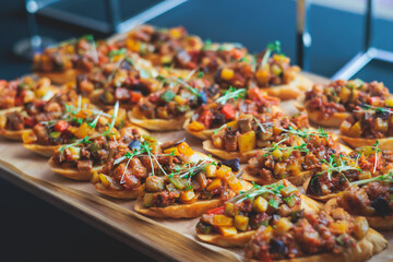 Beautifully decorated banquet catering table, with variety of with different food snacks appetizers on corporate birthday party event or wedding celebration, canape, salad, delicatessen setting