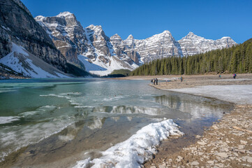 Unrecognizable people stand on the shore of Moraine Lake in the Valley of the Ten Peaks in Alberta, Canada