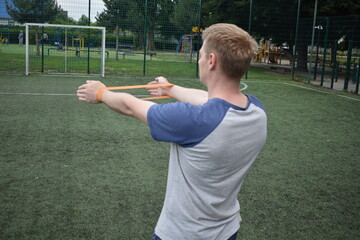 A young man in sportswear engages in a workout, using a sport tool for physical exercises on a...