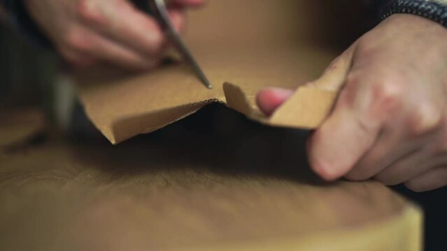 a man in a shirt cuts paper with scissors.
Man with scissors cutting a corton box
