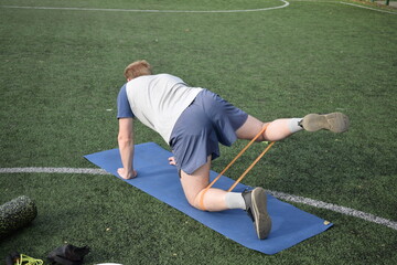 A young man in sportswear engages in a workout, using a sport tool for physical exercises on a...