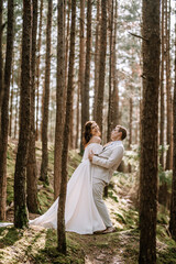 Valmiera, Latvia - September 9, 2023 - Bride and groom share a joyful moment in a forest, with the groom playfully dipping the bride, creating a whimsical and romantic scene.
