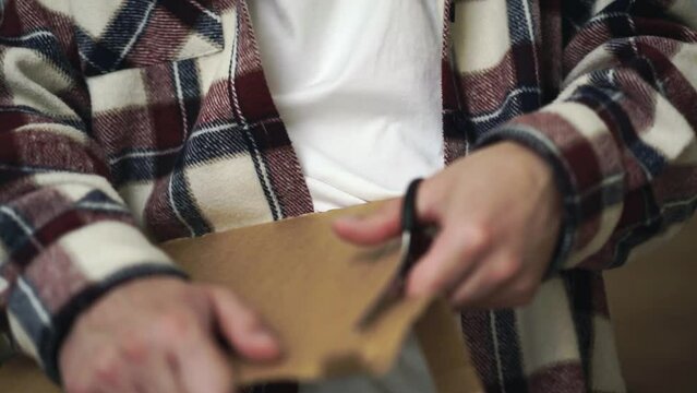Cardboard and scissors close-up.
A man cuts brown paper with scissors.
Sharp scissors cutting paper