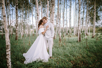 Valmiera, Latvia - September 9, 2023 - A bride and groom stand lovingly embraced in a serene birch...
