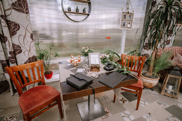 Valmiera, Latvia - September 9, 2023 - Cozy indoor seating area with two wooden chairs, a table with notebooks, small decorative items, and plants creating a charming atmosphere.