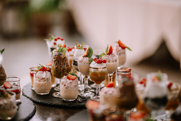 Valmiera, Latvia - September 9, 2023 - A variety of elegant dessert glasses filled with creamy treats, garnished with fresh fruits and mint leaves, arranged on a tray...