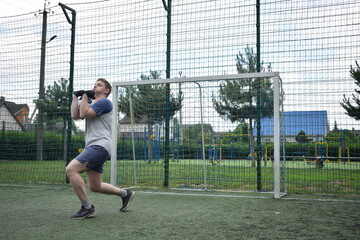 A young man in sportswear is playing soccer, training on a football pitch in the morning. Dedication and passion for the sport, the essence of morning exercise and practice outdoors