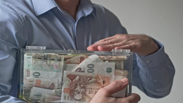 man rejoices, hugs tightly, and caresses a donation box filled with cash money banknotes