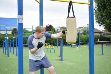A dedicated young athlete boxing, puts in the hard work, training on gym equipment outdoors to...