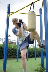 A dedicated young athlete boxing, puts in the hard work, training on gym equipment outdoors to...