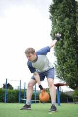 A young man in sportswear engages in a workout, using a sport tool for physical exercises on a...
