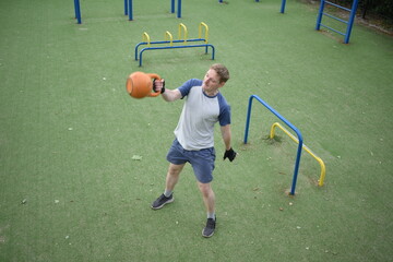 A young man in sportswear engages in a workout, using a sport tool for physical exercises on a...