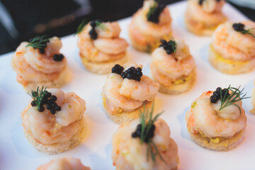 Beautifully decorated banquet catering table, with variety of with different food snacks appetizers on corporate birthday party event or wedding celebration, canape, salad, delicatessen setting